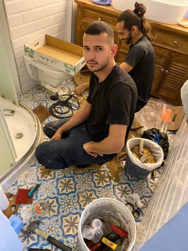 עידן אברהמי במהלך עבודת איתור ותיקון נזילה בחדר אמבטיה